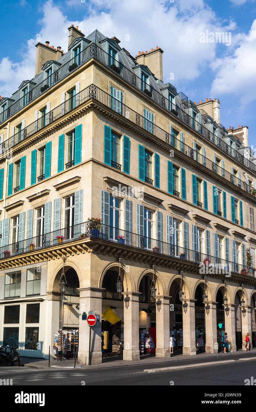 Un immeuble haussmannien typique à Paris avec balcons, volets, arcades et boutiques sous une lumière chaude de fin d'après-midi. Banque D'Images