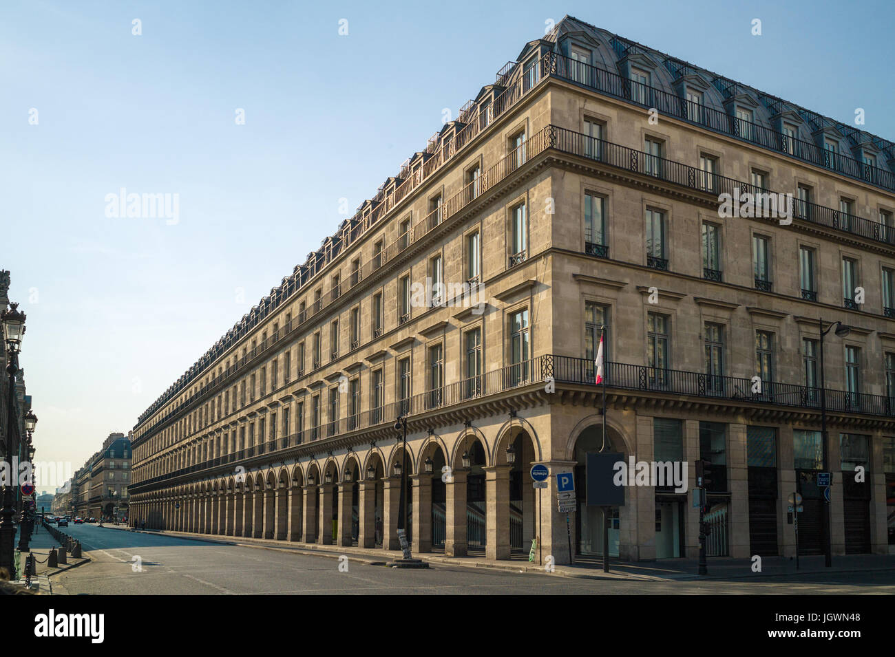 Un bâtiment de style typiquement Haussmann à Paris avec balcons, arcades et boutiques sous une lumière chaude de fin d'après-midi. Banque D'Images
