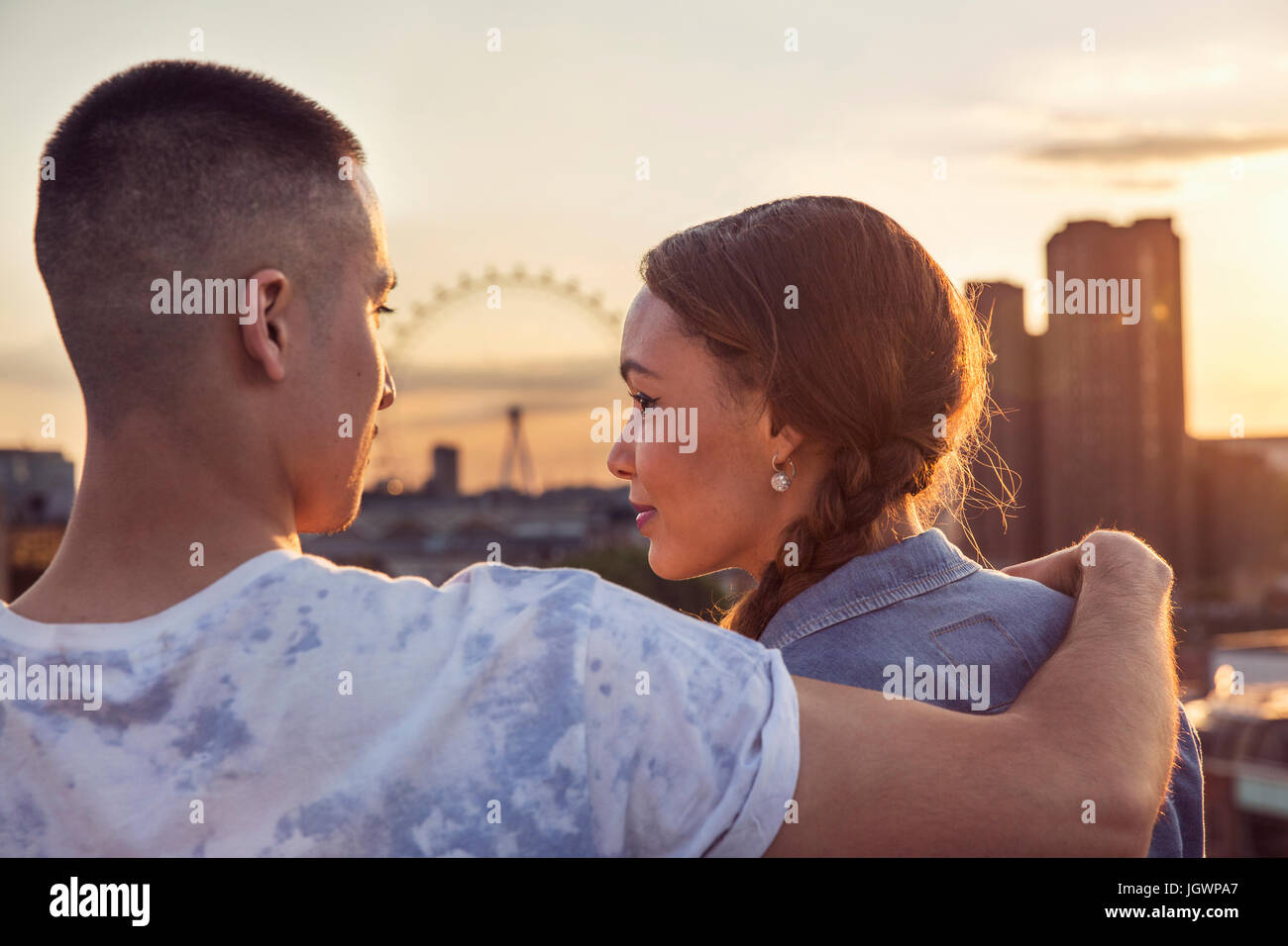 Jeune couple en face de toit Skyline at sunset party à Londres, Royaume-Uni Banque D'Images Jeune couple en face de toit Skyline at sunset party à Londres, Royaume-Uni Banque D'Images