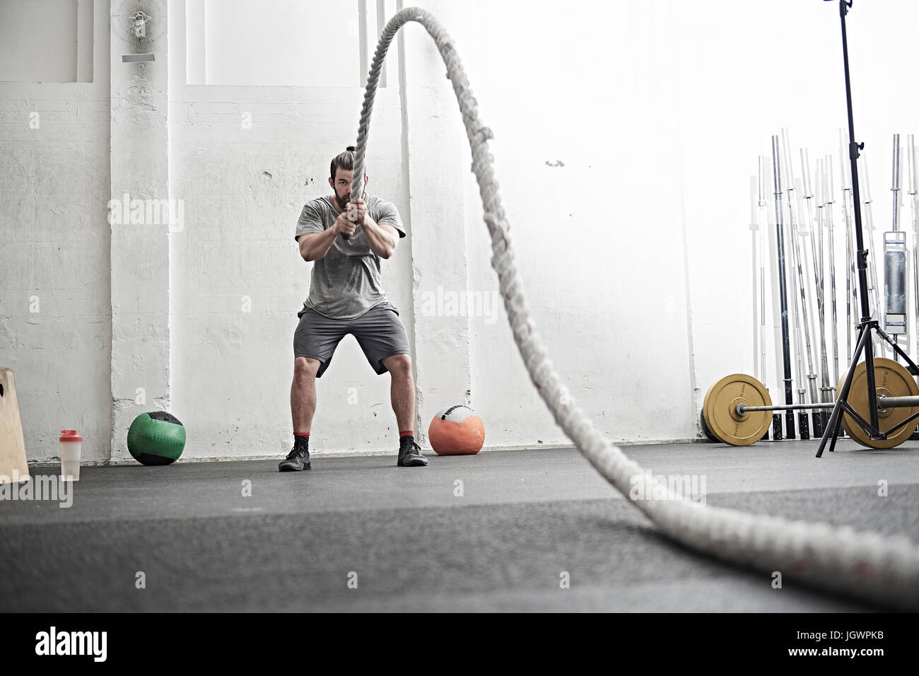 Homme travaillant sur la bataille avec la corde dans l'entraînement en salle de sport Banque D'Images