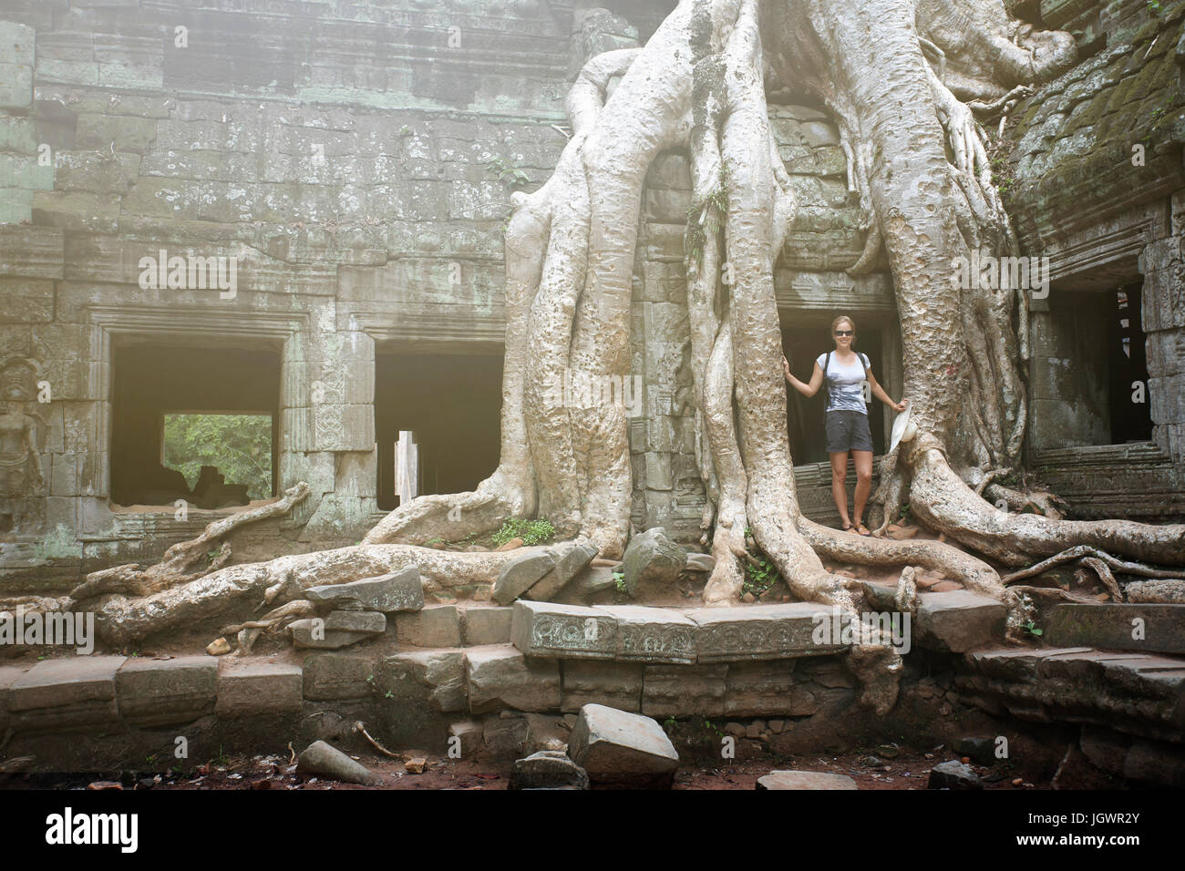 Portrait of young female tourist par les racines des arbres à Ta Prohm temple, Angkor, Siem Reap, Cambodge Banque D'Images