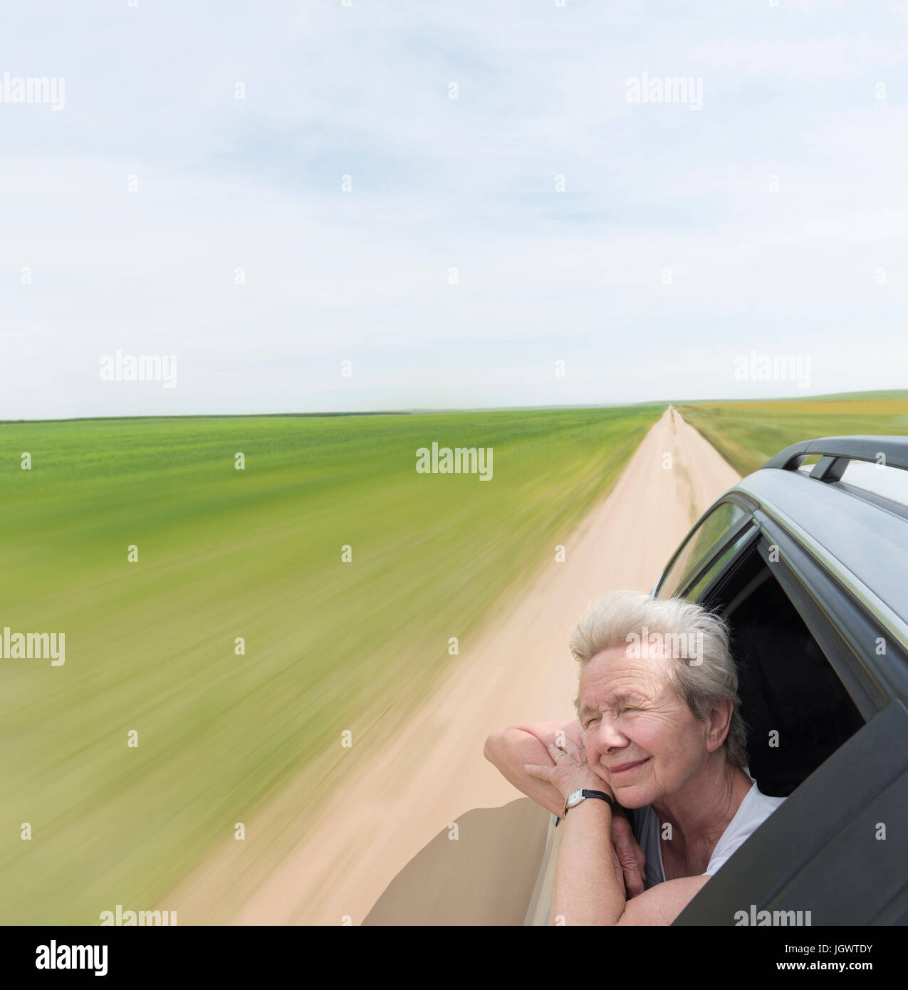 Senior woman leaning on car window appréciant le vent en face Banque D'Images