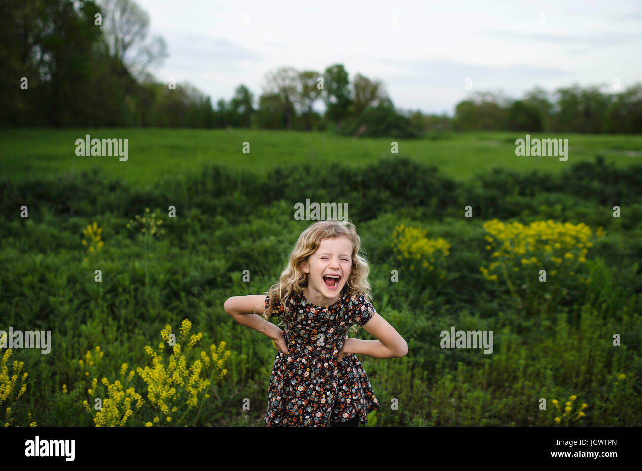 Portrait de jeune fille avec les cheveux blonds ondulés rire dans domaine Banque D'Images