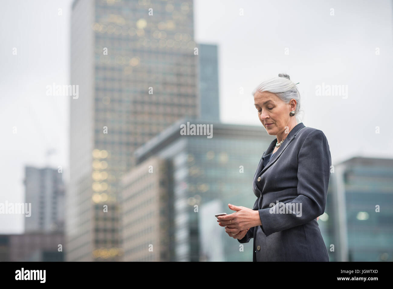 Businesswoman using mobile phone, Canary Wharf, London, UK Banque D'Images