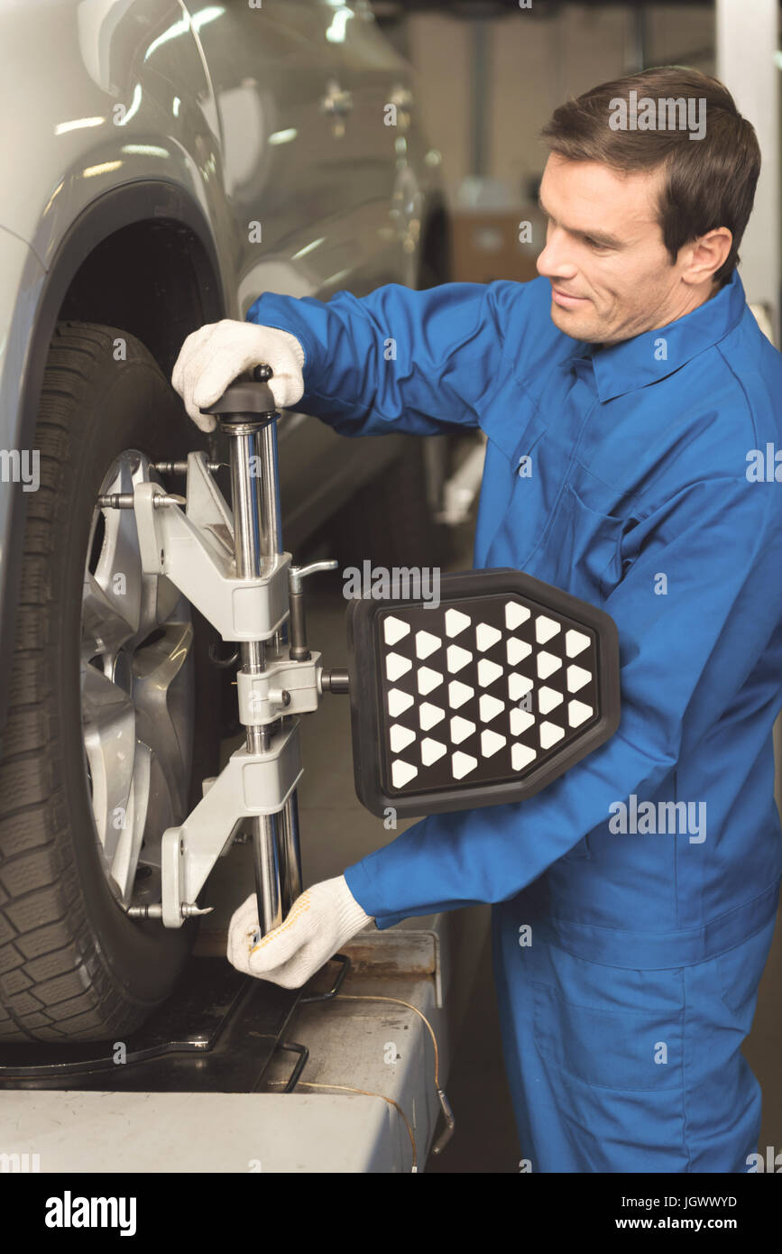 Spécialiste moderne. Homme d'expérience formés fiable d'effectuer un bilan sur les nouveaux pneus à l'aide de l'équipement professionnel de qualité et d'être très prudent Banque D'Images