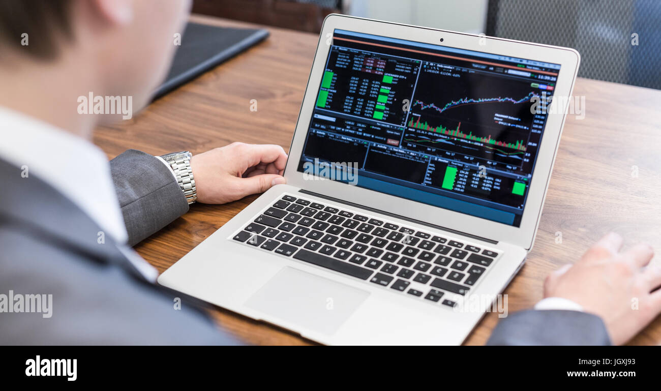 Jeune homme d'analyse des données économiques sur un ordinateur portable. Banque D'Images