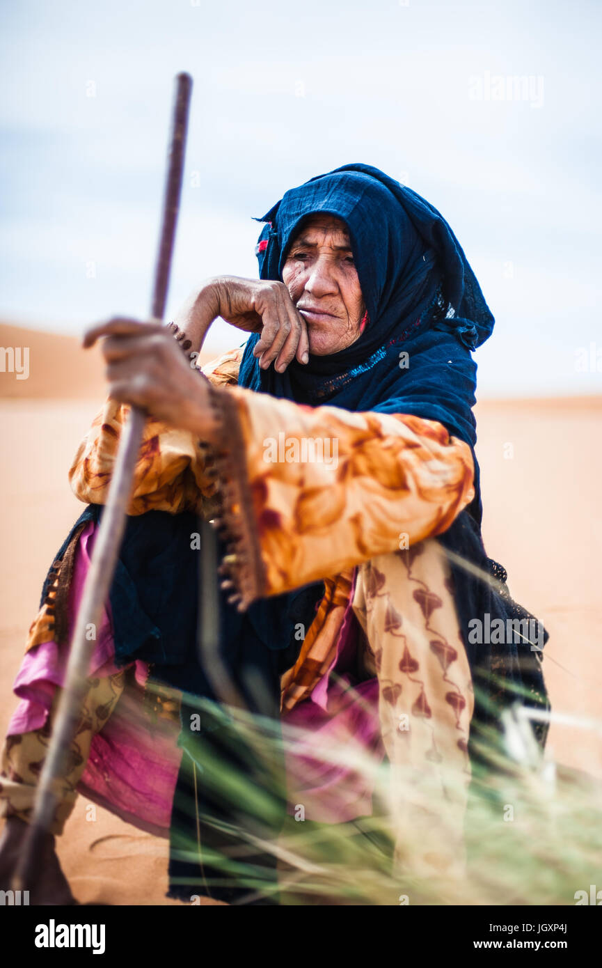 Portrait de vieille femme berbère assis sur une dune de sable à Merzouga, Maroc Banque D'Images