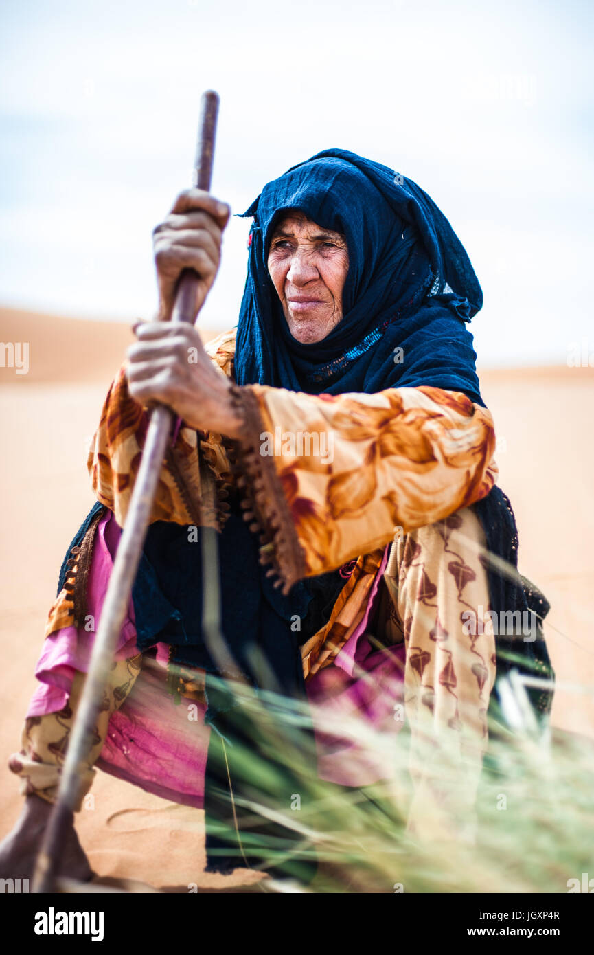 Portrait de vieille femme berbère assis sur une dune de sable à Merzouga, Maroc Banque D'Images