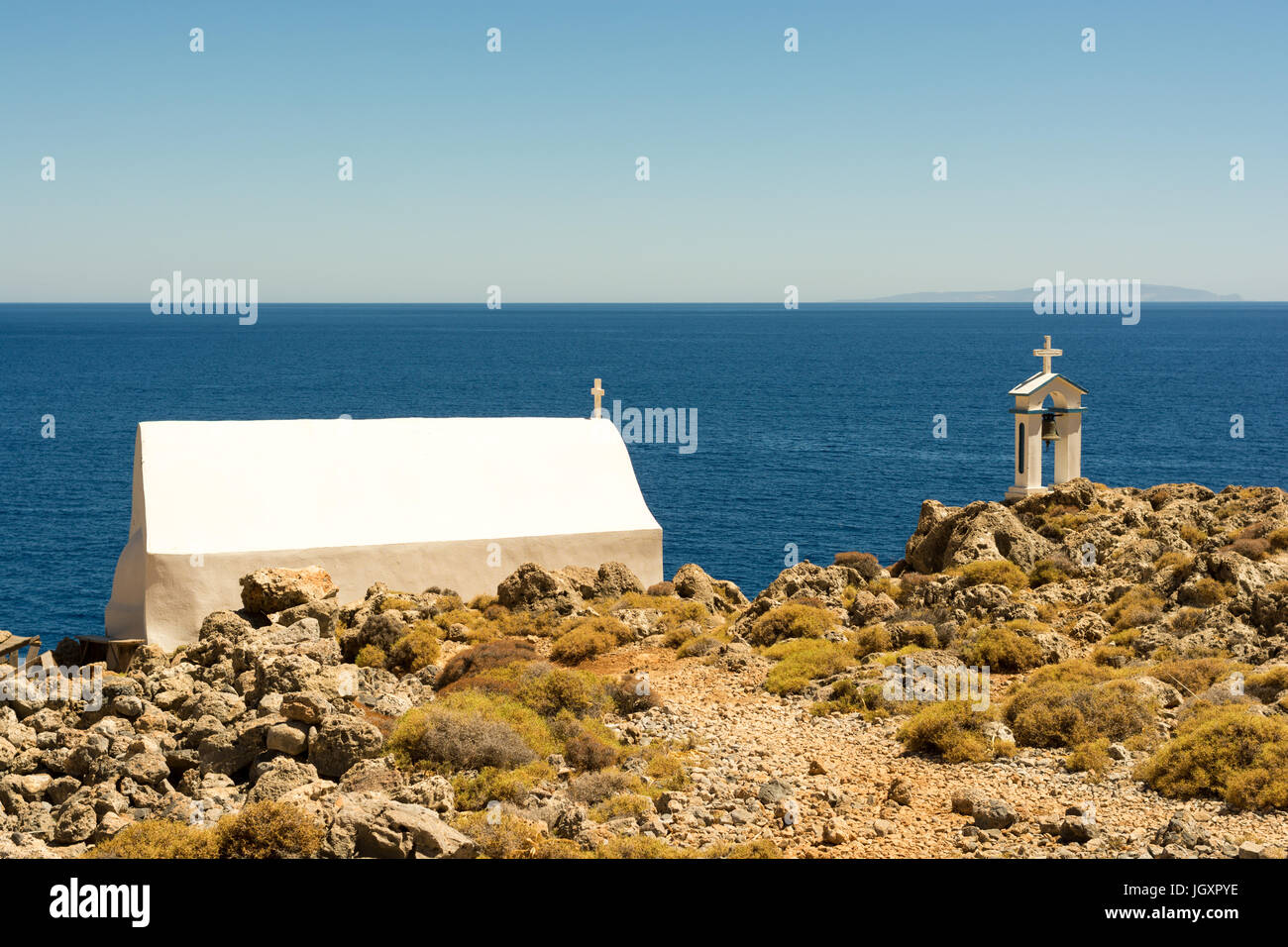 Petite, blanche, à distance de l'église grecque construite sur des rochers près de la mer sur la côte sud de l'ouest de la Crète, Grèce, avec un clocher séparé. Banque D'Images