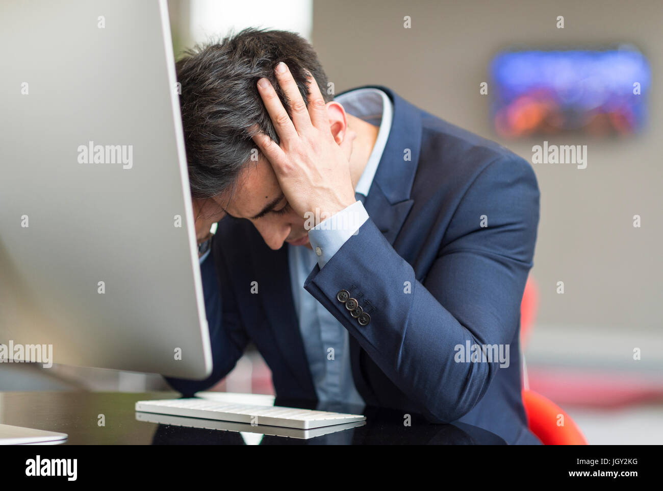 Ordinateur de bureau à stressed businessman with head in hands Banque D'Images