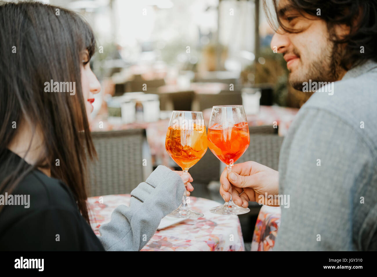 Young couple sitting Café à l'extérieur, tenant un verre, faire un toast Banque D'Images