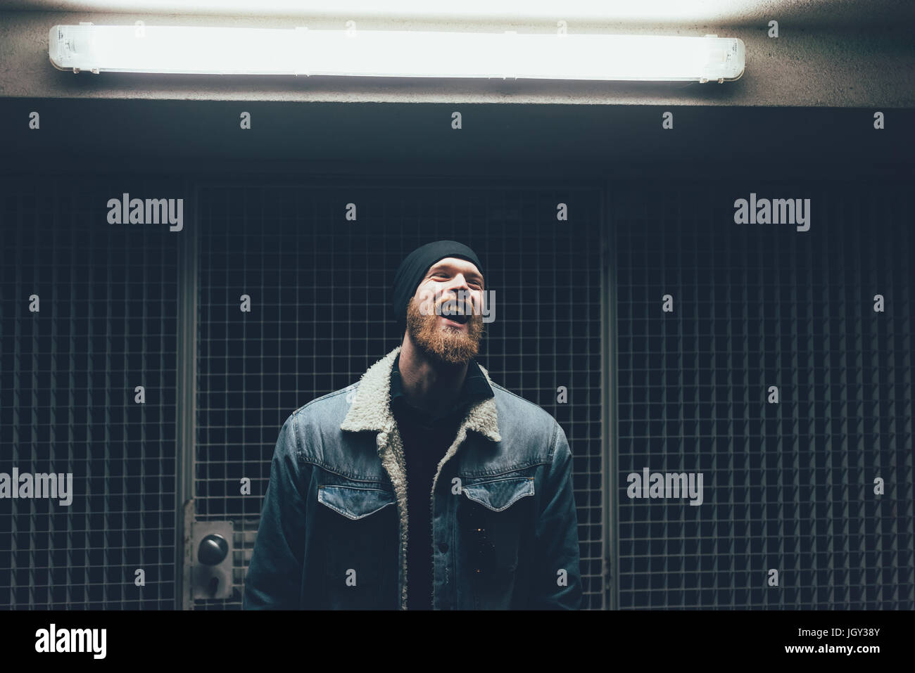 Jeune homme hipster rire dans Dark city porte à nuit Banque D'Images