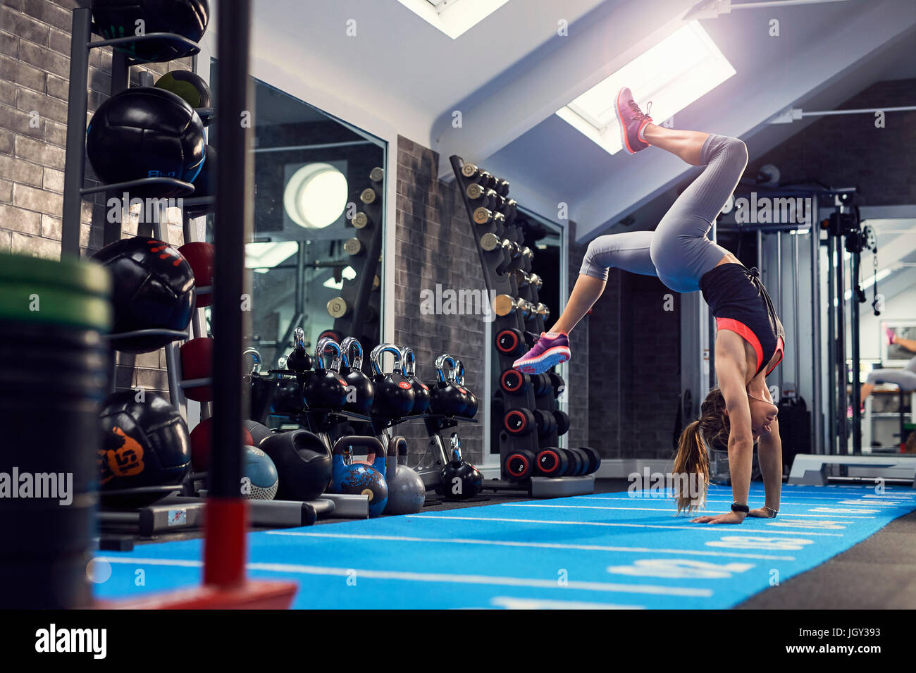 Young woman doing handstand, formation sur matelas de gymnastique Banque D'Images