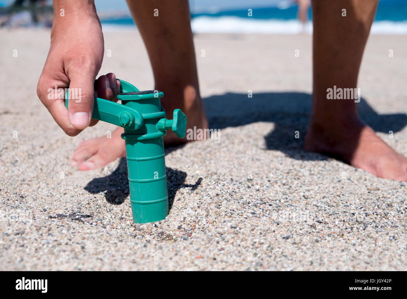 Libre d'un jeune homme de race blanche d'installer le grabber d'un parasol dans le sable d'une plage Banque D'Images