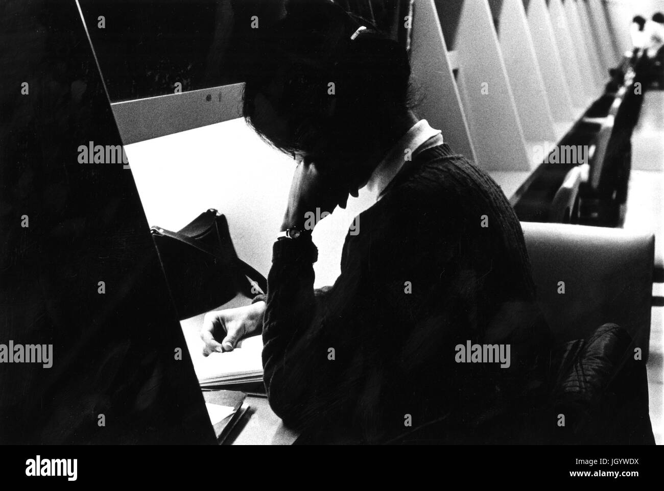 Un étudiant de l'Université Johns Hopkins est assis à une station d'étude, la lecture avec sa tête reposant sur sa main, dans l'université, Milton S Eisenhower Library, à Baltimore, Maryland, 1965. Banque D'Images