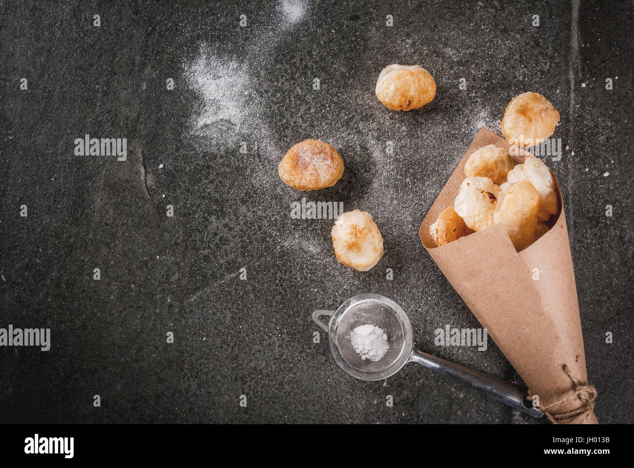 La cuisson à la maison, les feuilletés. La nourriture à la mode. Cronuts popcorn, puff, trous de beignes dans sac en papier avec du sucre en poudre. Sur une table en pierre. Copy space Banque D'Images