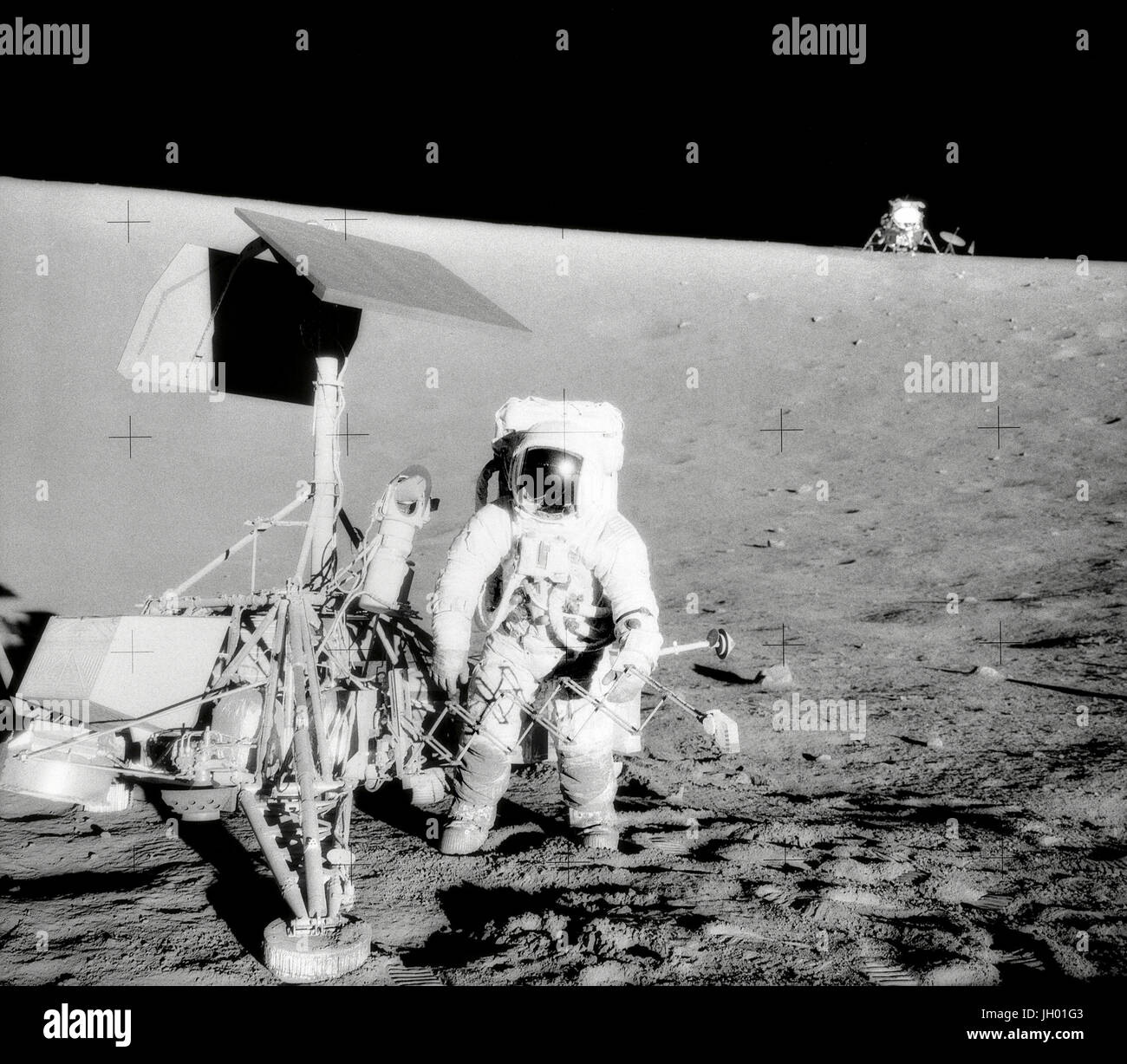 Conrad et arpenteur sur la pente d'un cratère. Charles Conrad Jr., commandant de la mission Apollo 12, examine l'engin spatial non habité Surveyor III pendant la seconde activité extravéhiculaire (EVA-2). Le Module lunaire (LM) 'Intrepid' est dans l'arrière-plan droit. Cette photo a été prise par l'astronaute Alan Bean L., pilote du module lunaire. L 'Intrepid' s'est posé sur la Lune's Ocean des tempêtes à seulement 600 pieds de Surveyor III. La caméra de télévision et plusieurs autres composants ont été prises à partir de Surveyor III et ramenés à terre pour l'analyse scientifique. Surveyor III soft à l'atterrissage sur la lune le 19 avril 1967. Banque D'Images