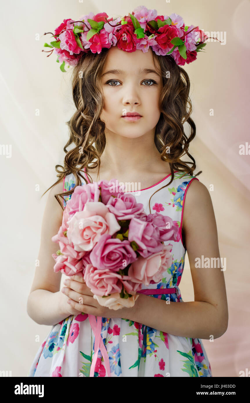 Portrait of cute little girl à Nice, robe de printemps avec couronne de fleurs sur la tête, est titulaire d'un bouquet de fleurs Banque D'Images