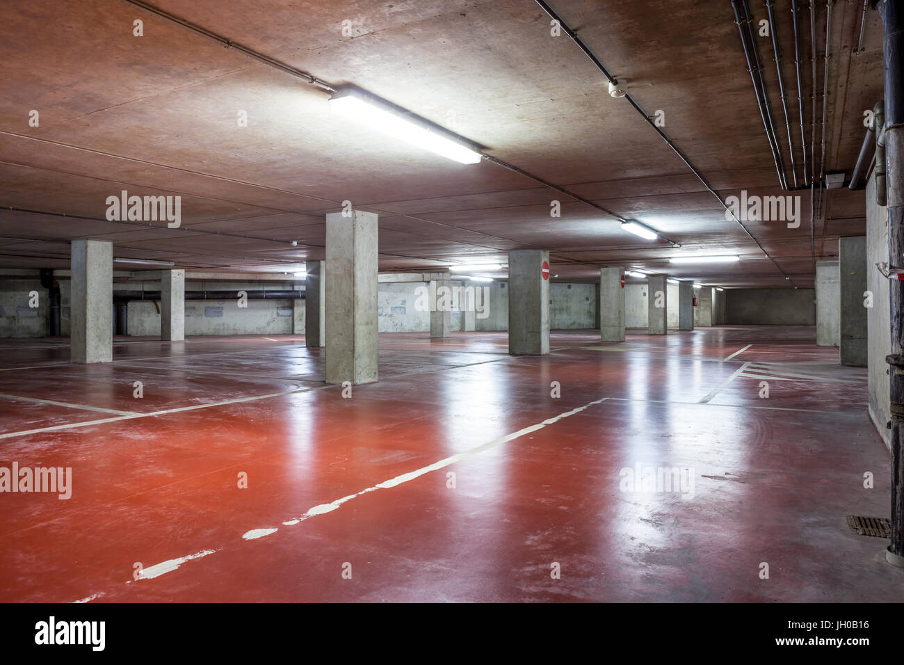 Parc souterrain d'un centre commercial avec des colonnes et des conduits de ventilation Banque D'Images