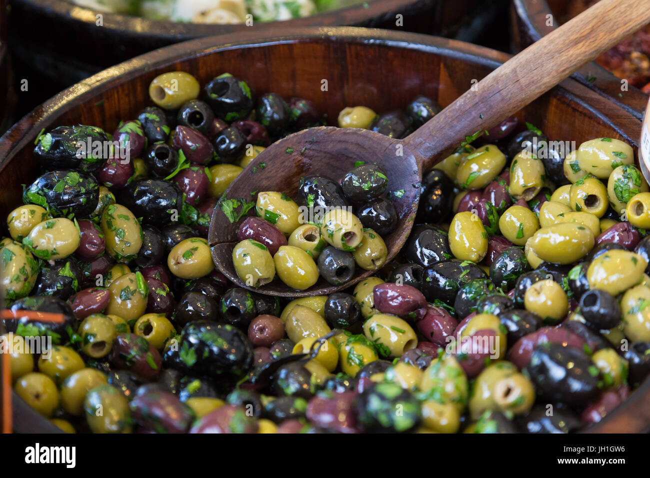 Olives en bols en bois avec une cuillère de service. Banque D'Images