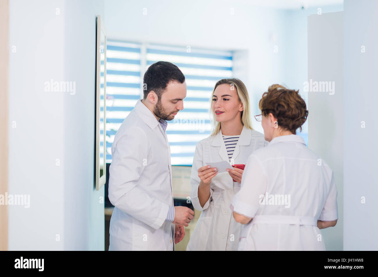 Mature doctor discuter avec les infirmières dans un couloir l'hôpital. Discuter de l'état du patient médecin avec son personnel médical après l'opération. Banque D'Images