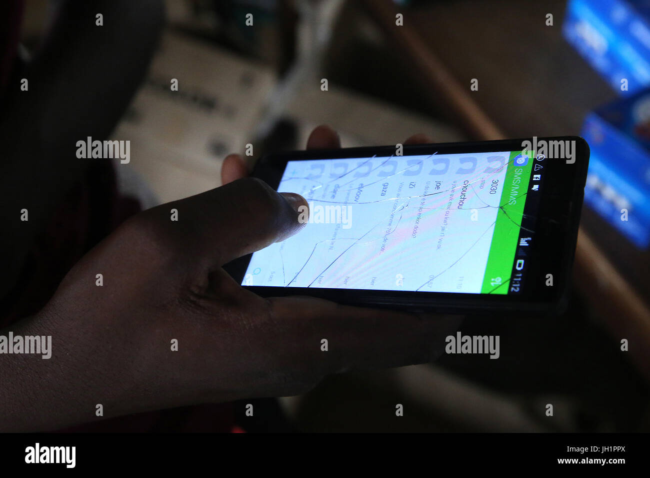 Portrait d'un homme africain en utilisant un téléphone intelligent avec un écran fissuré. Lome. Le Togo. Banque D'Images