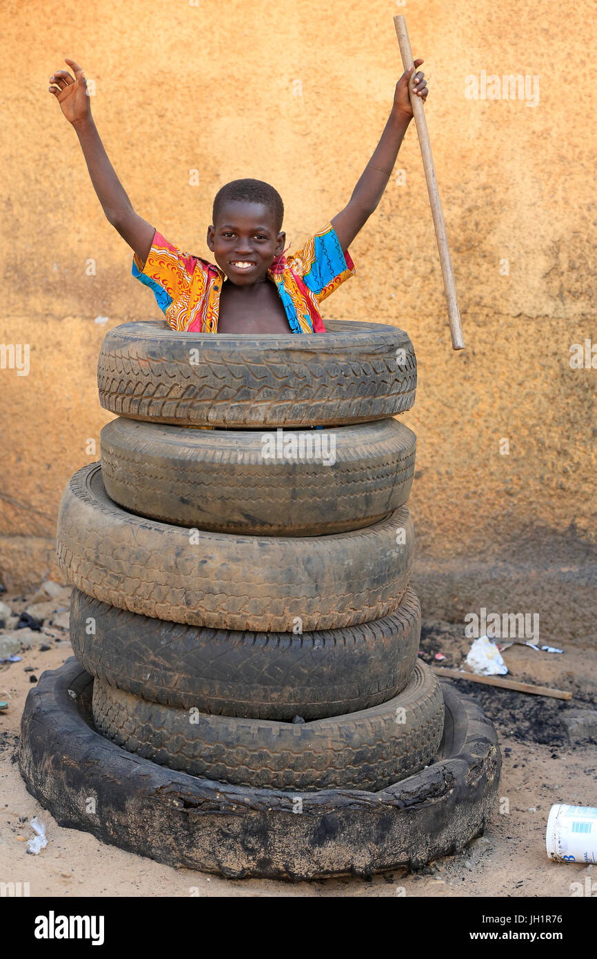 Jeune garçon africain plaing avec de vieux pneus. Lome. Le Togo. Banque D'Images