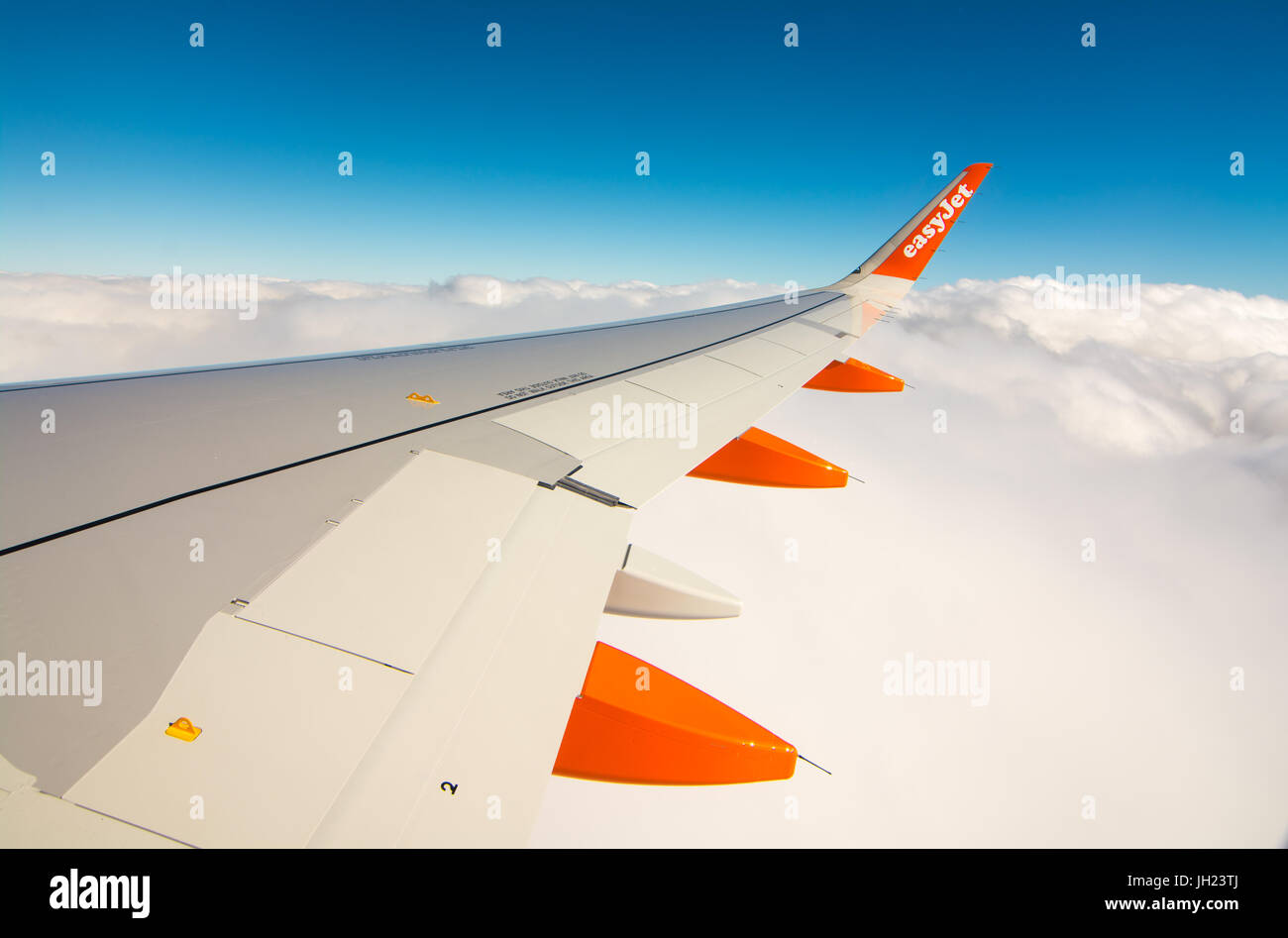 Orange et blanc sur l'aile d'un Airbus d'Easyjet s'élevant au-dessus des nuages blancs moelleux. Banque D'Images
