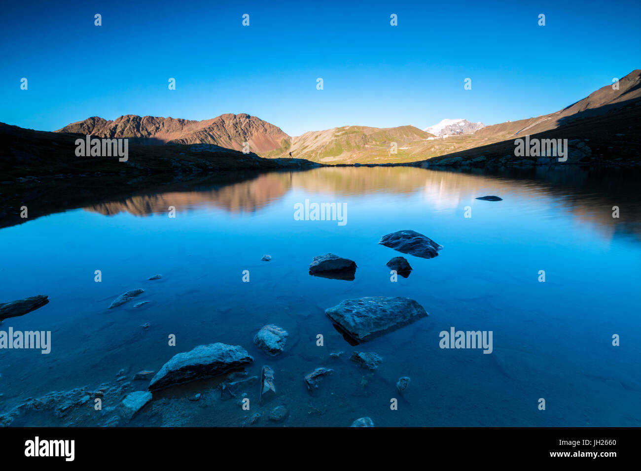 Les pics rocheux reflété dans le lac Umbrail au coucher du soleil, col du Stelvio, Valtellina, Lombardie, Italie, Europe Banque D'Images