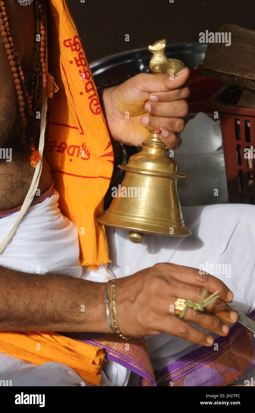 Prêtre hindou. Close up of hand holding bell de cérémonie. Singapour. Banque D'Images