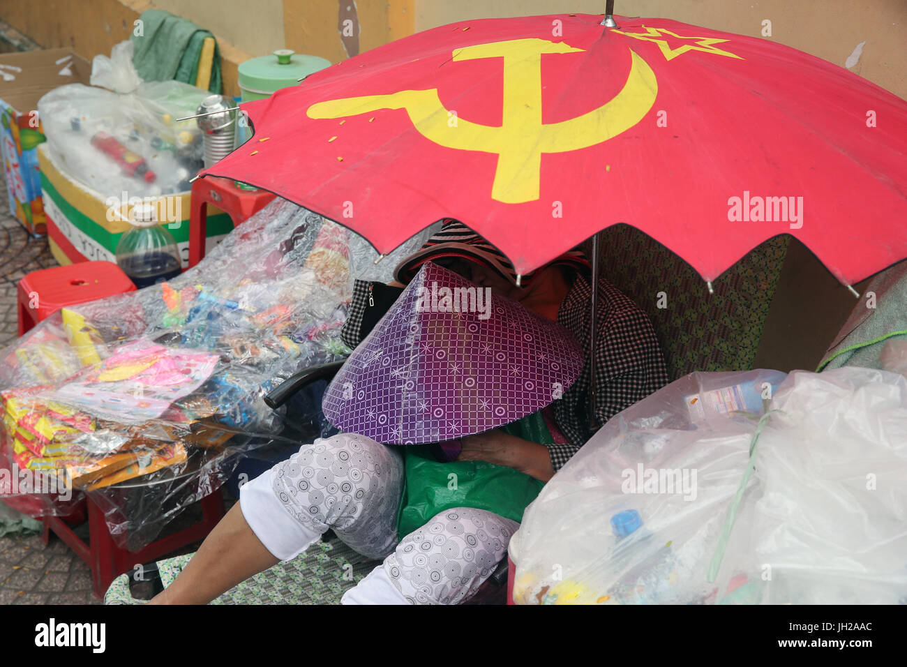 Femme dormir sous un parapluie communiste. Ho Chi Minh Ville. Le Vietnam. Banque D'Images