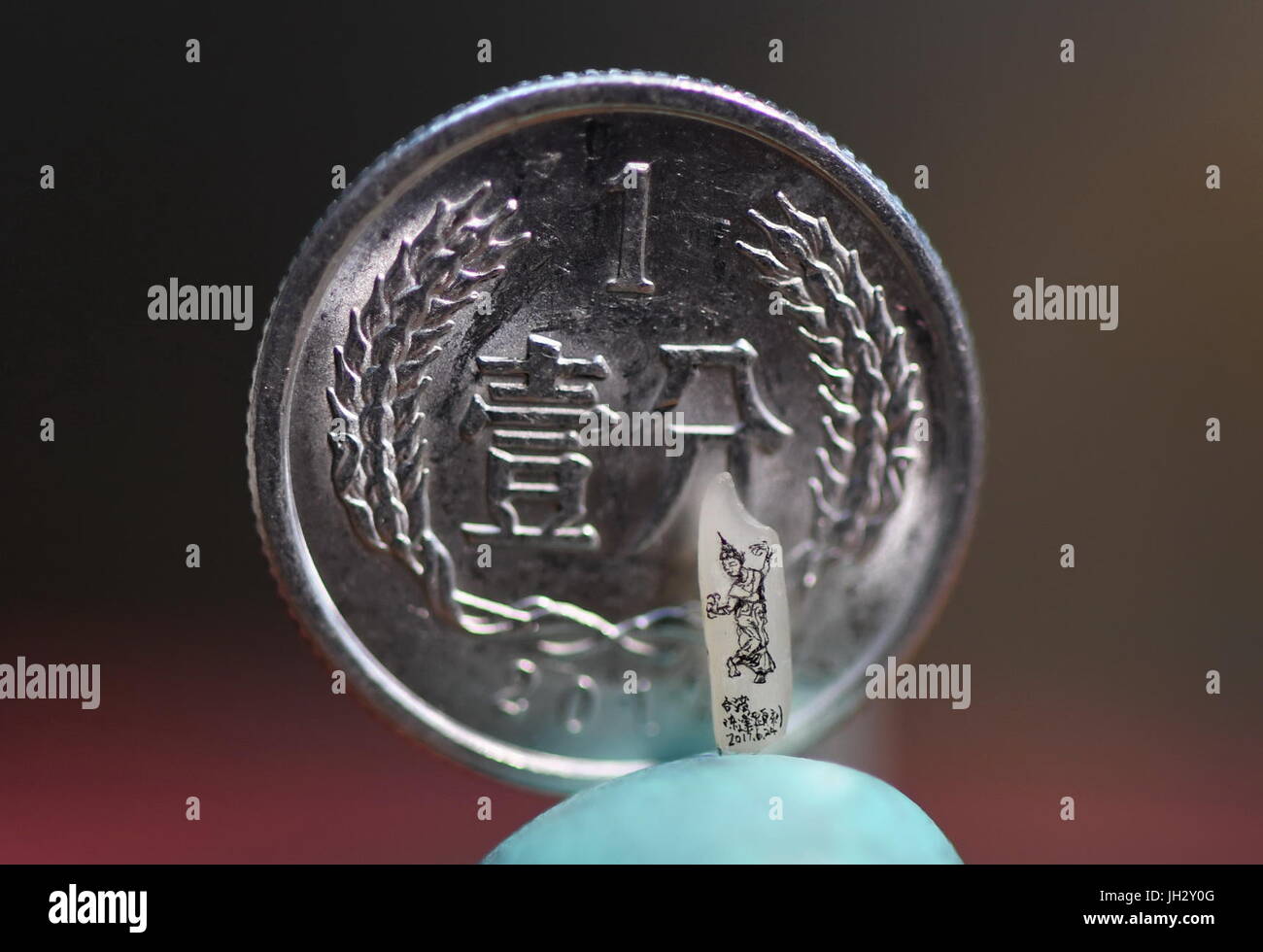 Taipei. 12 juillet, 2017. Photo prise le 12 juillet 2017 montre une sculpture miniature du riz à l'aide d'une pièce en arrière-plan fait par Chen Fengxian, une sculpture artiste à Taipei, Taiwan de la Chine du sud-est. Chen a travaillé sur la sculpture miniature pendant plus de 30 ans, la sculpture avec des matériaux tels que le riz, l'or et le bois. Les sculptures miniatures il fait peut même se tenir sur la tête d'une épingle. Credit : Zhou Mi/Xinhua/Alamy Live News Banque D'Images