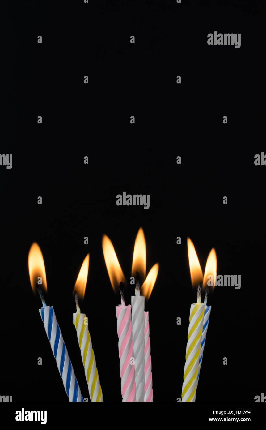 Sept bougies du gâteau d'anniversaire à rayures descendre en flammes sur un tableau noir à l'arrière-plan copie espace ci-dessus. Banque D'Images