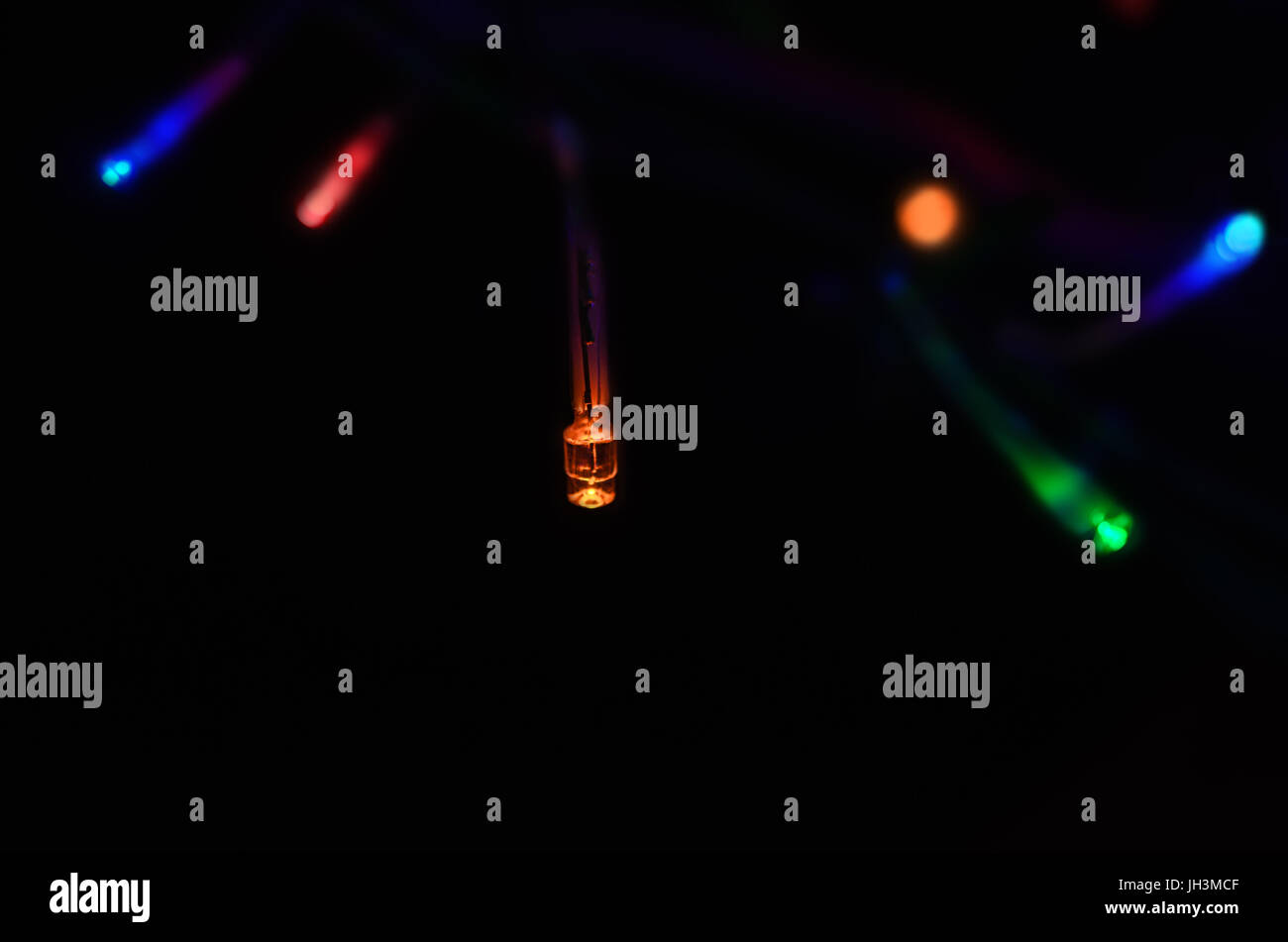 Fairy lights shining de fond noir sur une chaîne dans une variété de couleurs. Feux arrière-plan sont flous en soft focus. Banque D'Images