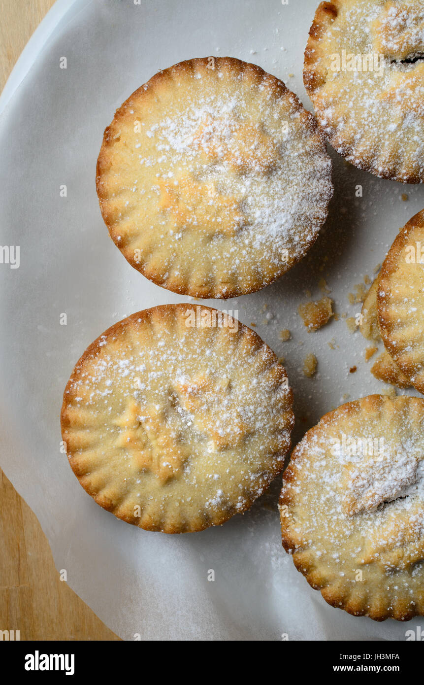 Coup de frais généraux de plusieurs petits pâtés de Noël, saupoudrés de sucre glace et disposées en cercle sur une assiette blanche. Banque D'Images