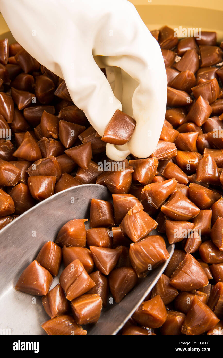 La production artisanale de bonbons bonbons au caramel caramel caramel.  Femme avec des gants blancs, secouer, mis en pot, obtenez dans l'pichets  les morceaux de beurre Photo Stock - Alamy