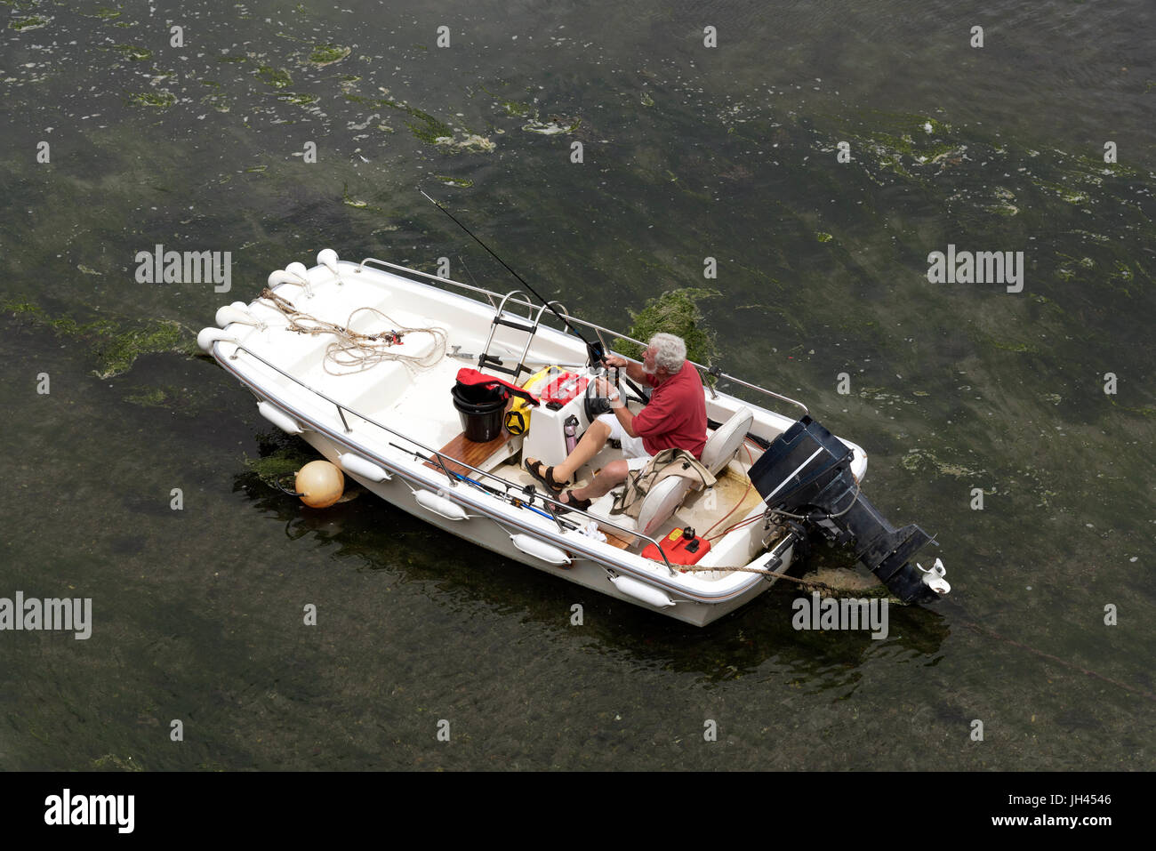 Sommaire d'un homme dans un bateau préparer sa canne et à la ligne pour un voyage de pêche Banque D'Images