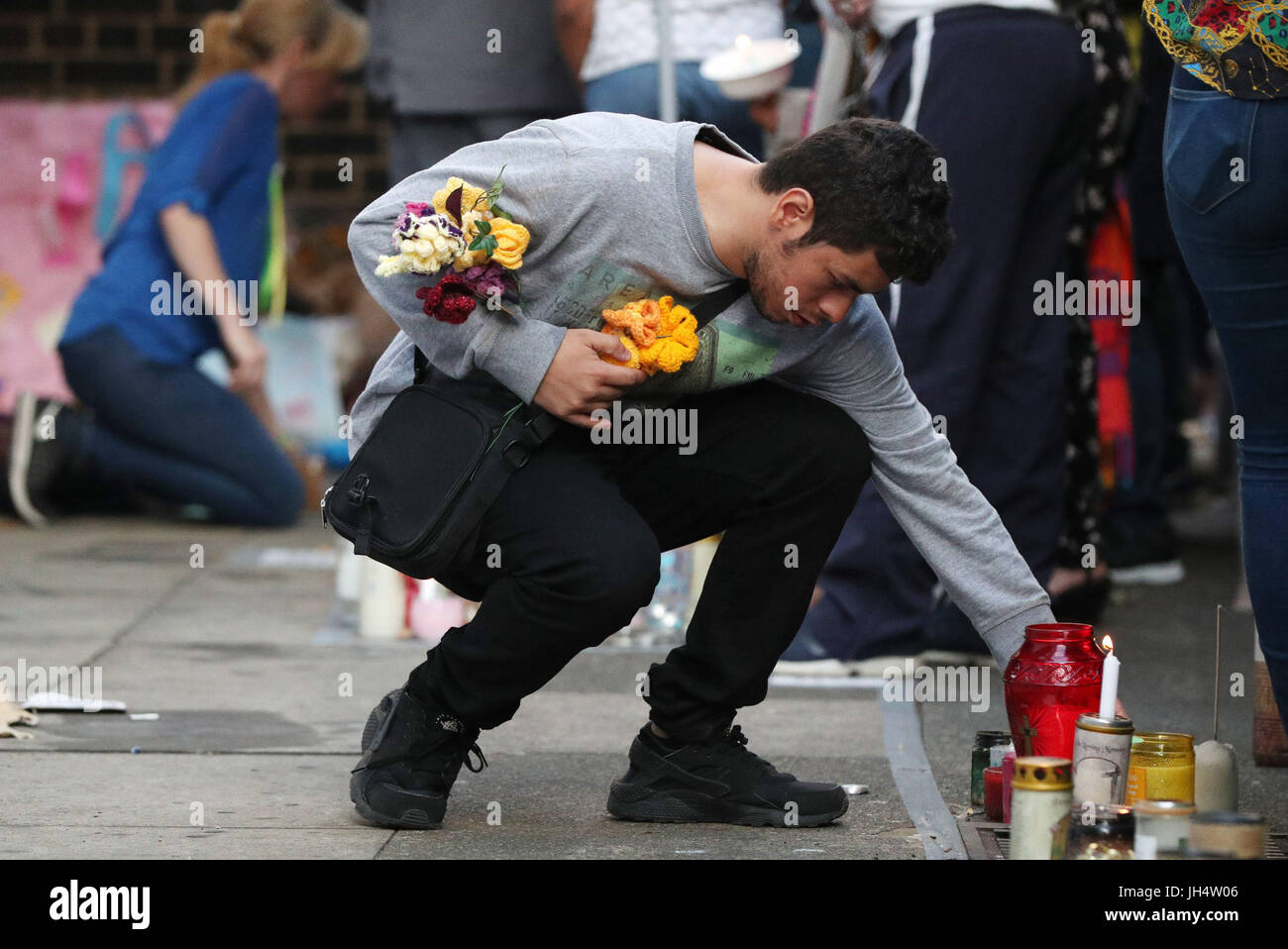 Un homme met des fleurs sur le mur commémoratif sur Bramley Road, Londres, en tant que personnes participent à une veillée pour marquer quatre semaines depuis la tour de Grenfell incendie. Banque D'Images