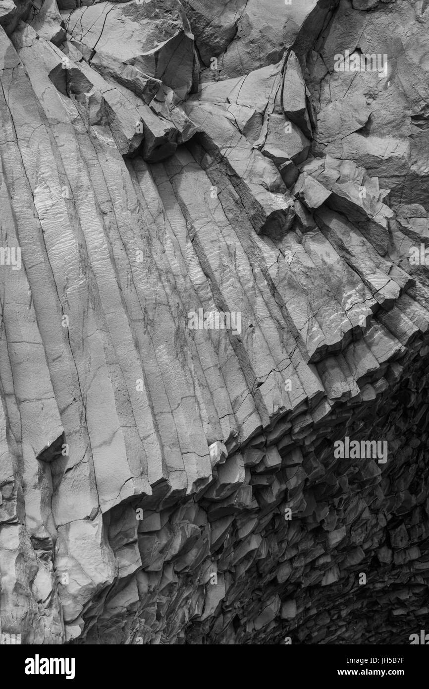 Image en noir et blanc de colonnes de basalte à l'entrée d'une grotte de la mer sur la plage de Reynisfjara qui jouit en Islande Banque D'Images