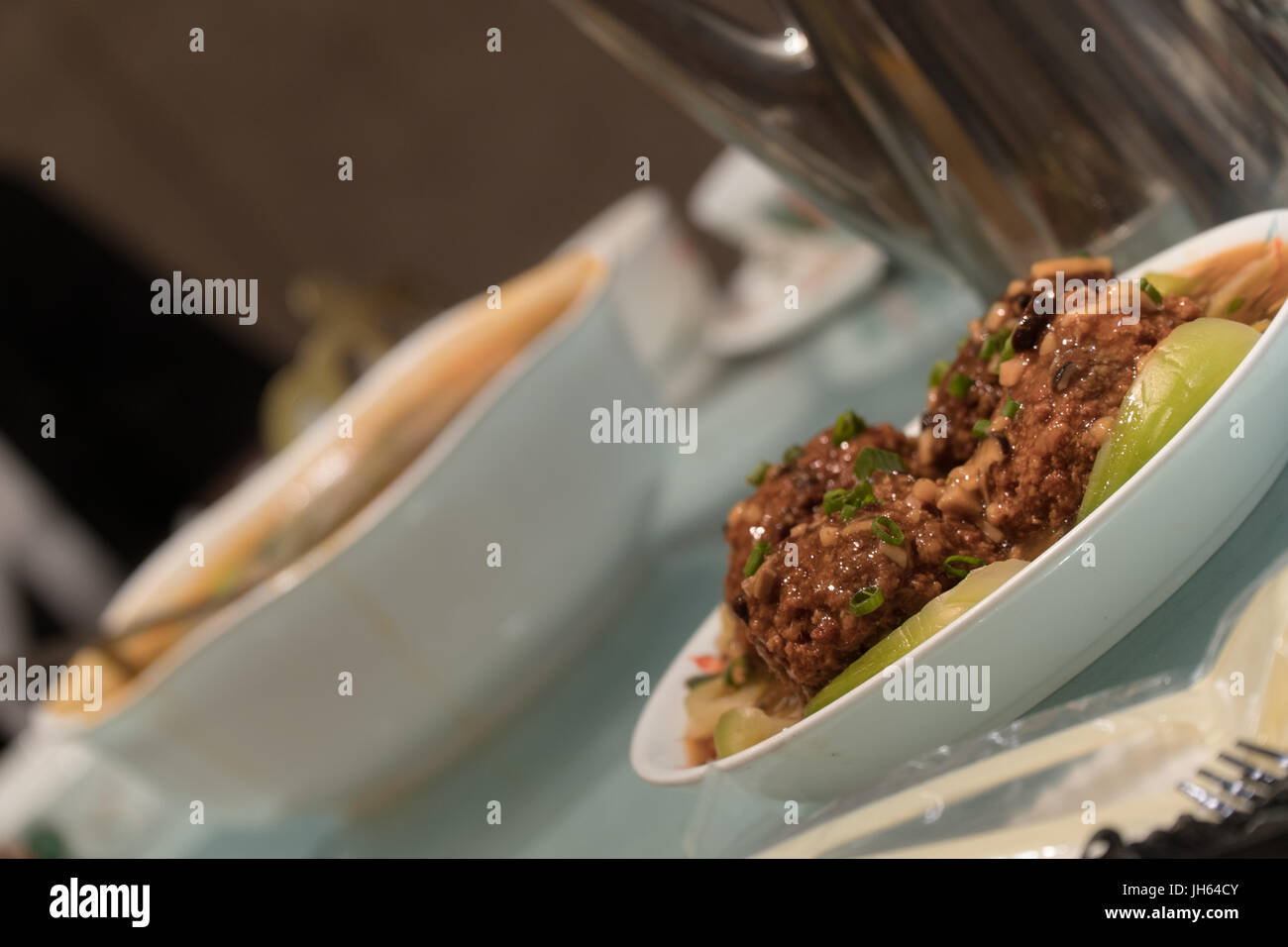 Tête de Lion Chinois boulettes de porc servi dans un restaurant table entre autres plats et ustensiles. Banque D'Images