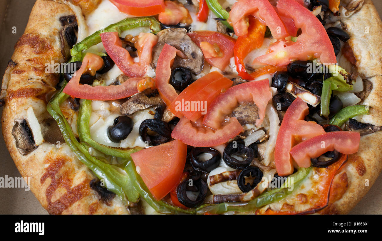Gros plan sur pizza végétarienne avec tomates, olives noires, champignons, oignons, poivrons et mozzarella Banque D'Images