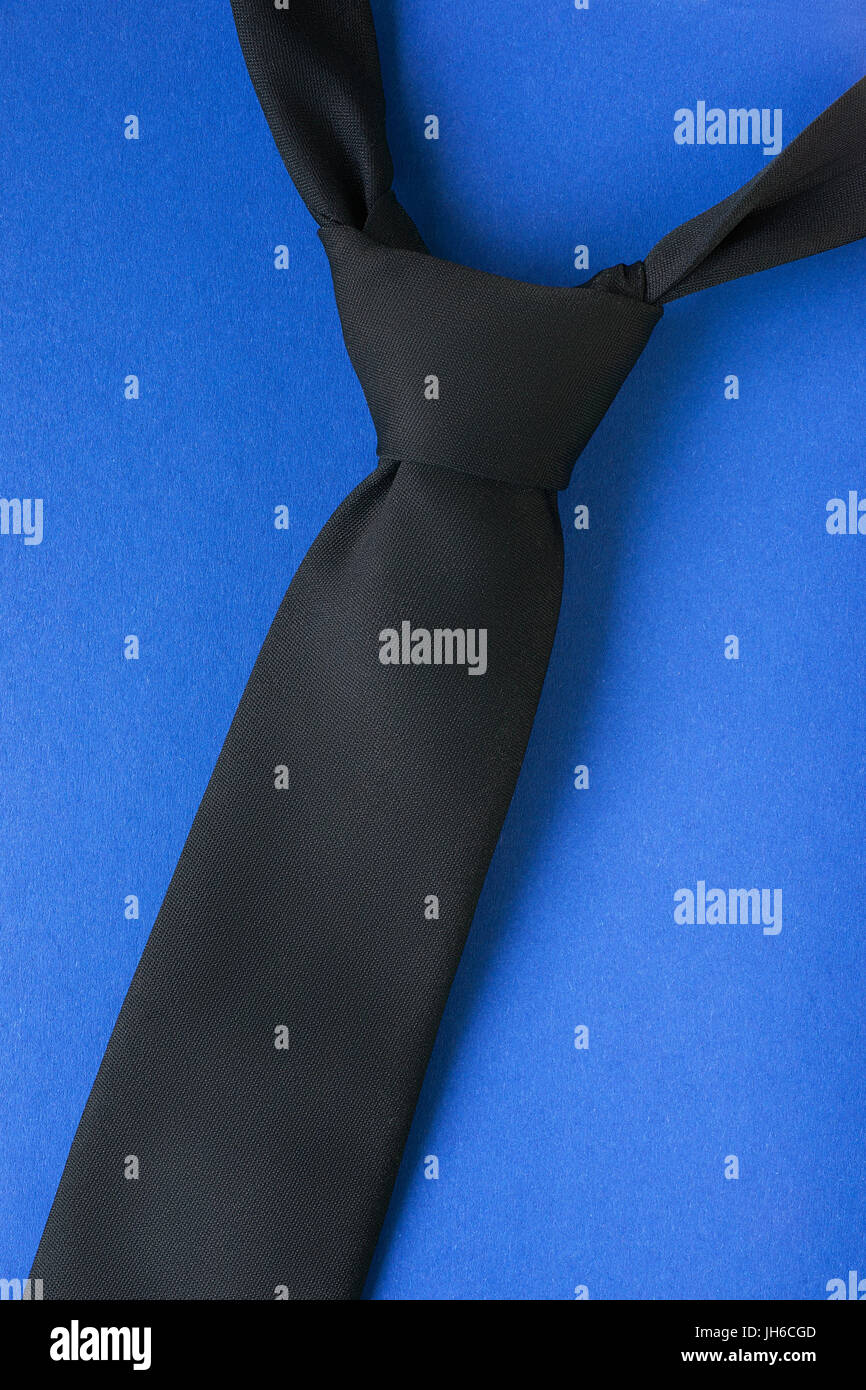 Cravate noire avec nœud windsor sur fond bleu. Thème style homme Banque D'Images