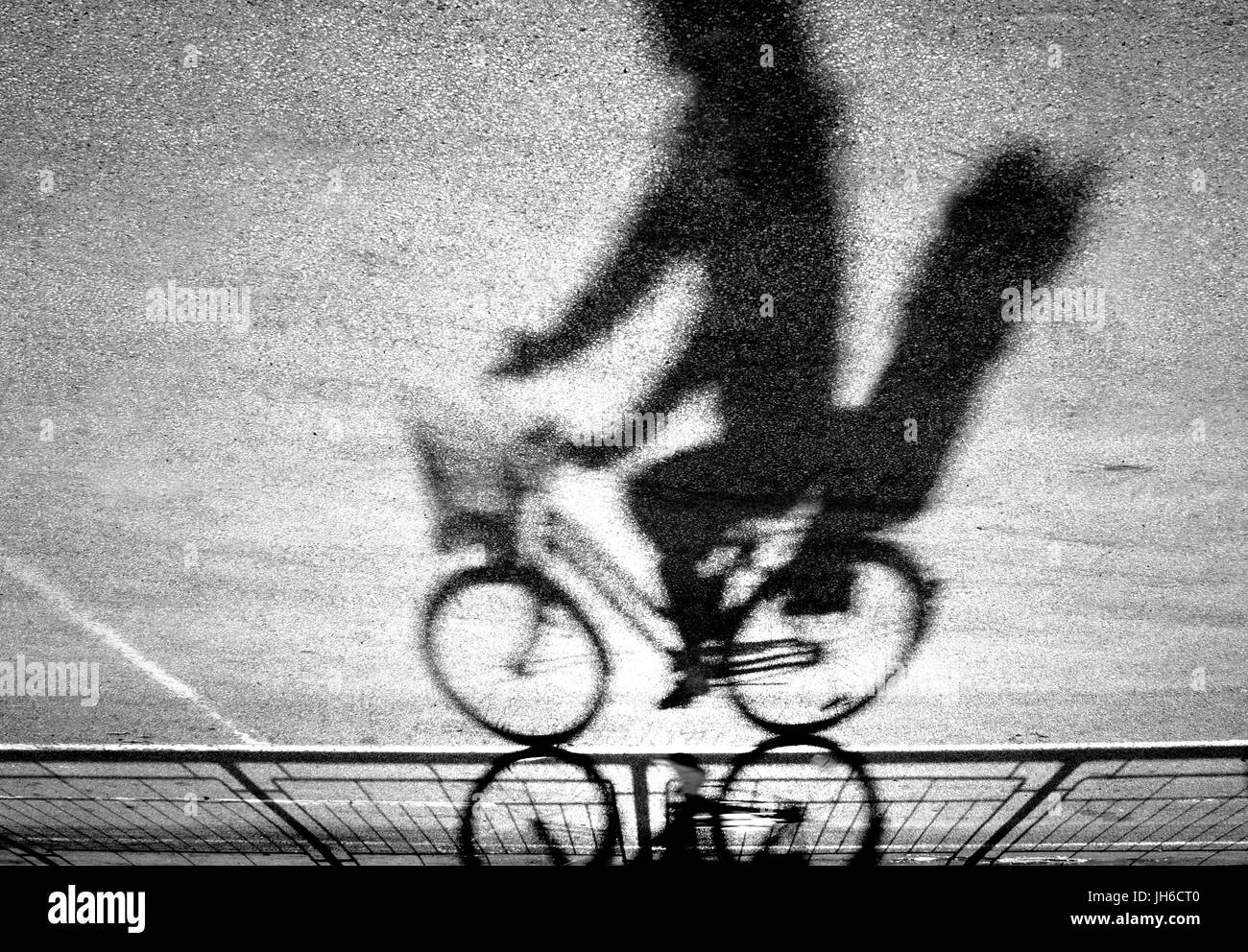 Cycliste avec kid floues silhouette de siège arrière et l'ombre sur une piste cyclable protégée en noir et blanc à l'envers Banque D'Images