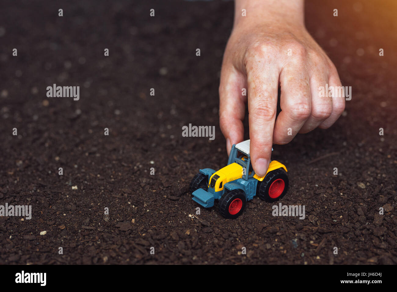 Farmer jouant avec petit tracteur agricole jouet sur sol fertile ground  Photo Stock - Alamy