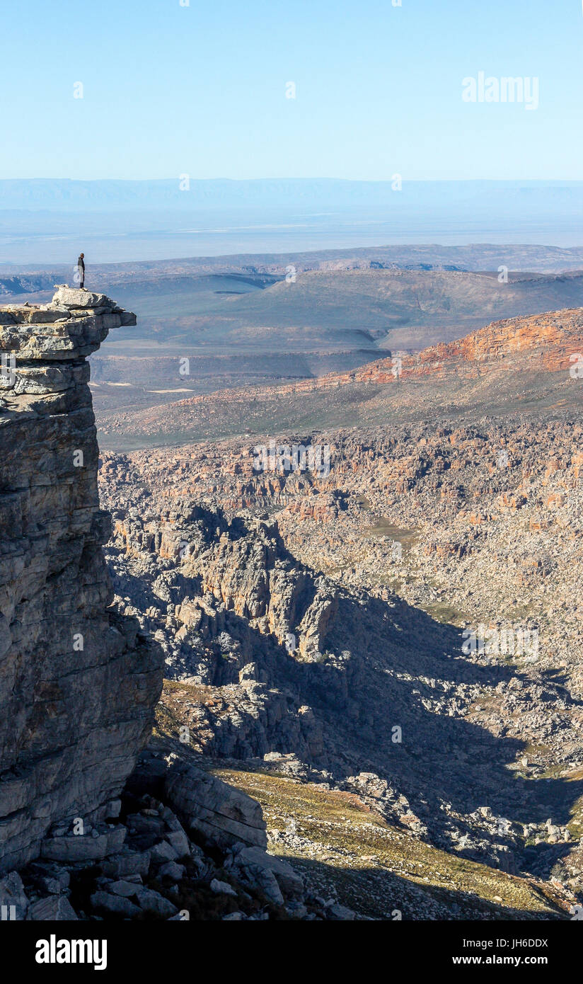 Randonneur debout sur un éperon rocheux dominant la vallée de montagne pittoresque Banque D'Images