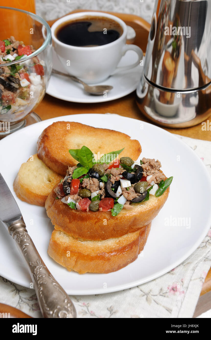 Petit déjeuner de pain frit avec des morceaux de thon avec l'oeuf, les cubes de tomates et les tranches d'olives, câpres avec une tasse de café, un pot de café sur un plateau Banque D'Images