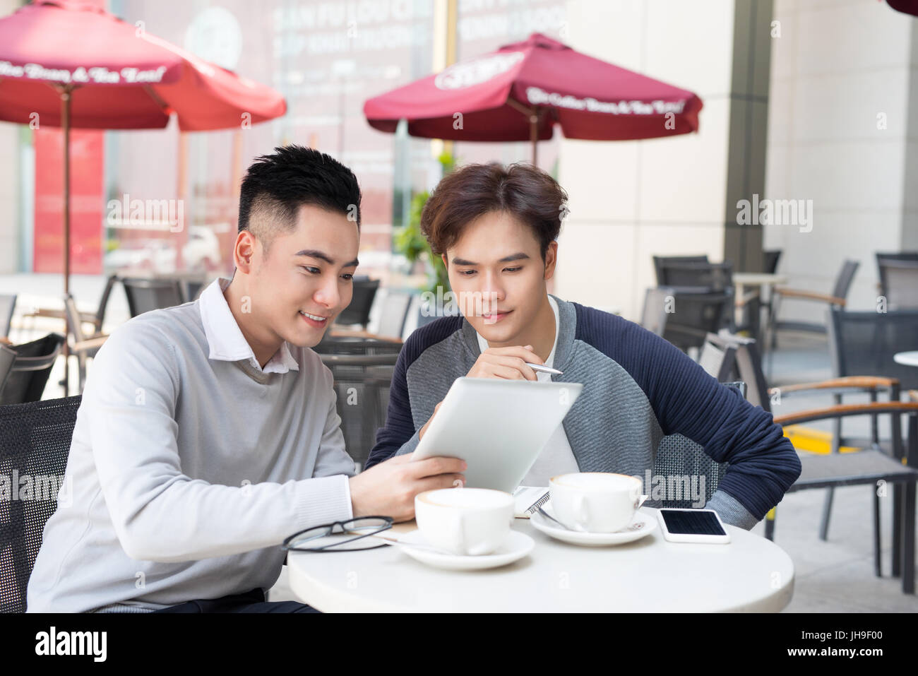 Deux jeunes hommes d'affaires dans les tenues de beau sourire, parler dans un café. Banque D'Images