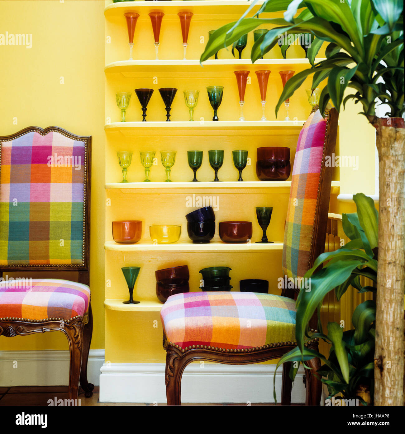 Chaises colorées par des étagères de verrerie Banque D'Images