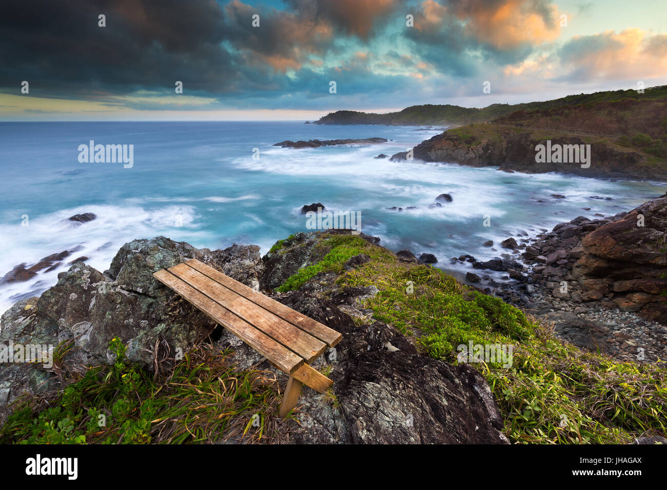 Un banc en bois avec vue sur une belle côte rocheuse au coucher du soleil en Australie. Banque D'Images