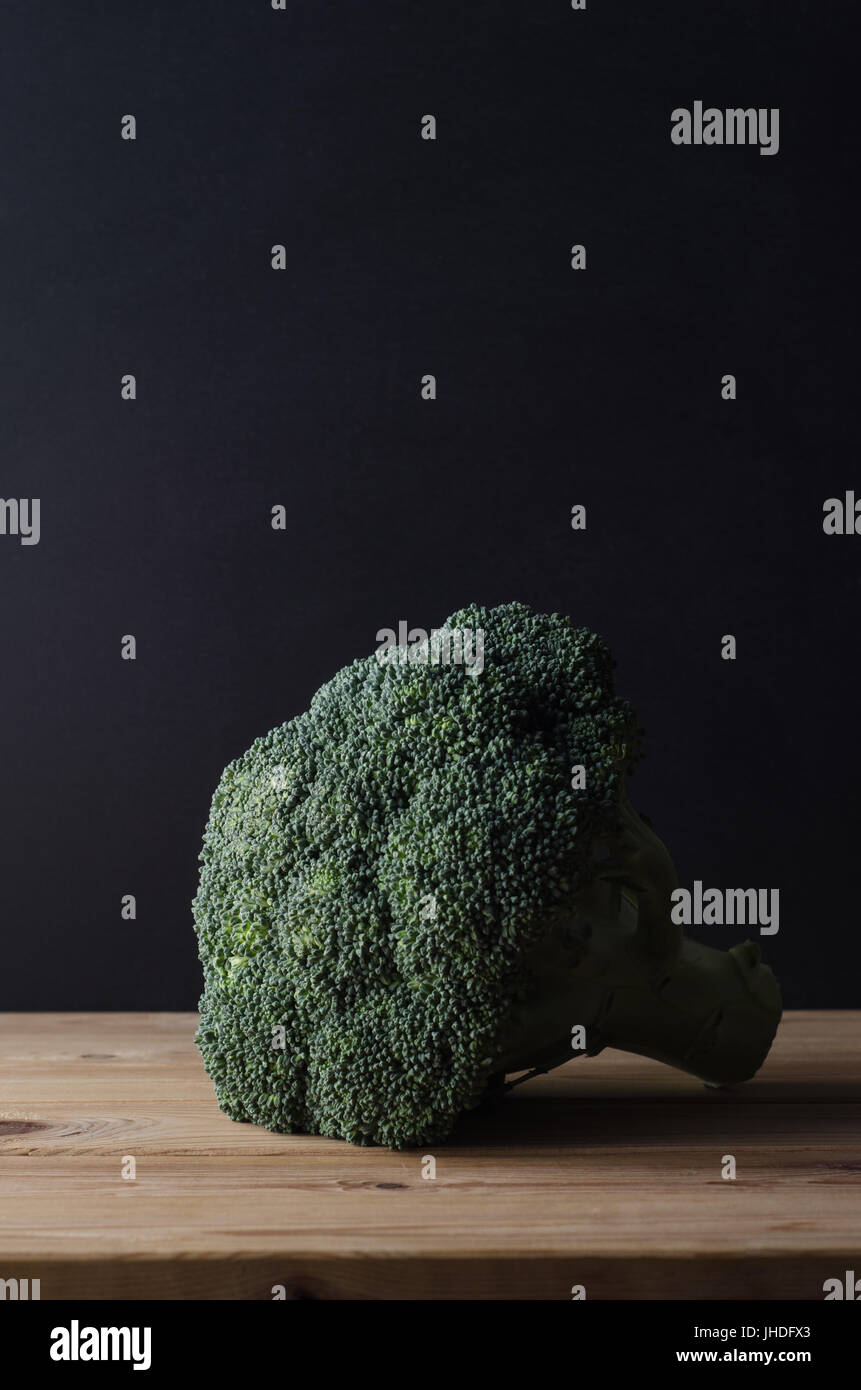 Une tête de brocoli vert foncé" avec planches en bois intact, sur tableau noir tableau contre l'arrière-plan. Moody l'éclairage. Banque D'Images
